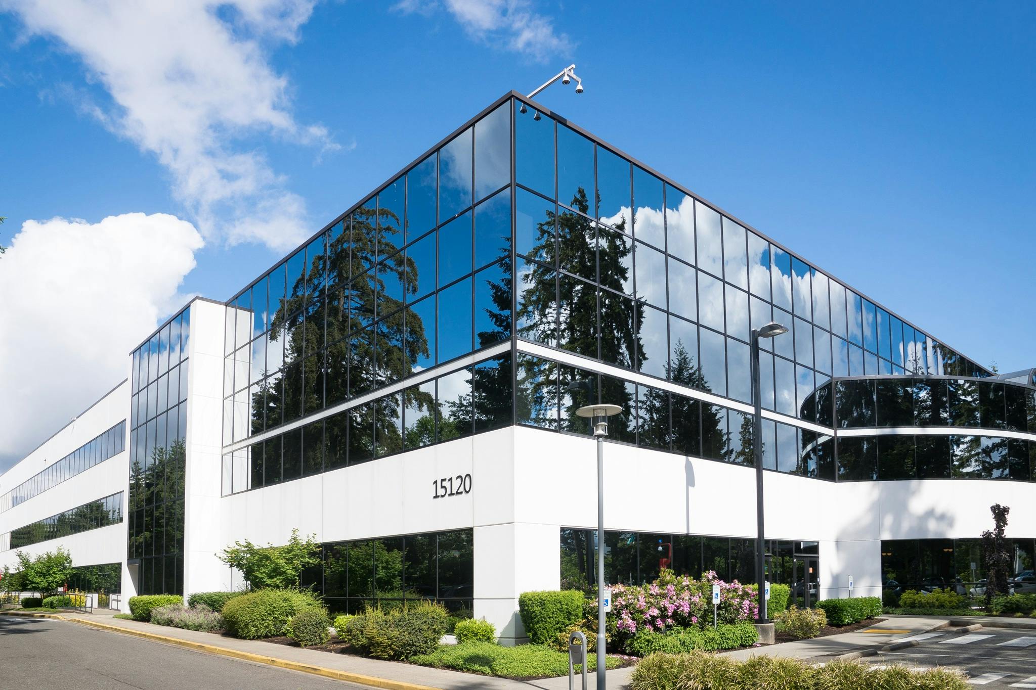 Contemporary office building in Redmond with reflective glass and lush greenery, captured on a sunny day.